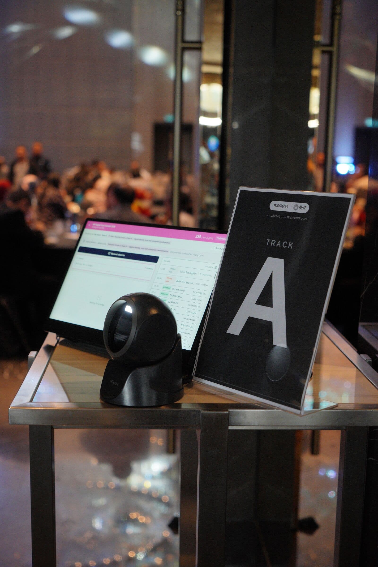 Self-service check-in kiosk with a scanner and a 'Track A' sign, MY Digital Trust Summit 2026